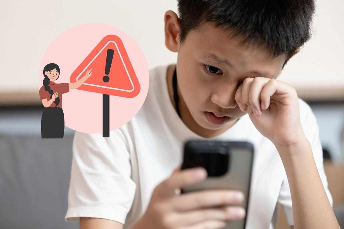 bambino con lo smartphone in mano e un segnale di pericolo